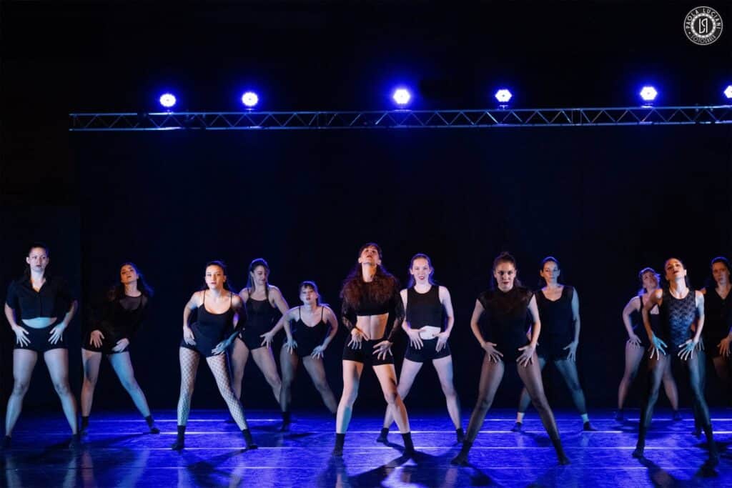 Three confident dancers performing against a purple gradient backdrop, showcasing dynamic movement and individual style in artistic lighting